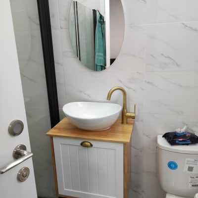 כיור עגול עם ברז זהב על ארון עץ