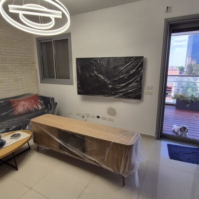 חדר מגורים עם רהיטים מכוסים בניילון, ללא סימני אינסטלציה.