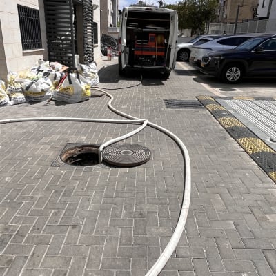 משאית ואקום עם צינור ליד פתח ביוב
