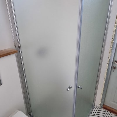 מקלחון זכוכית עם דלתות מתכת בחדר אמבטיה