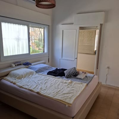 חדר שינה עם מיטה זוגית, חלון ומנורה תלויה