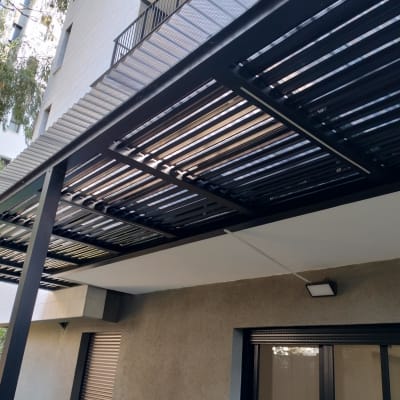 פרגולה מתכתית עם קורות עץ בגינה