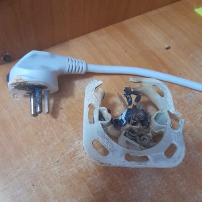 תקע חשמלי שרוף ושקע פגום על שולחן עץ