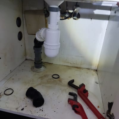 כלי עבודה וצנרת מתחת לכיור במטבח