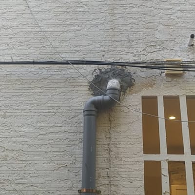 צינור ביוב אפור מחובר לקיר חיצוני