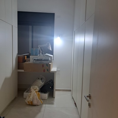 חדר עם ארונות לבנים, מנורה ושקיות על הרצפה