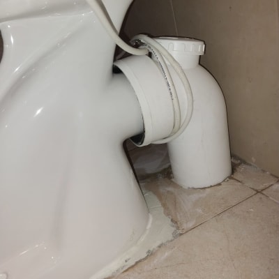 אסלה עם חיבורי צנרת על רצפת קרמיקה