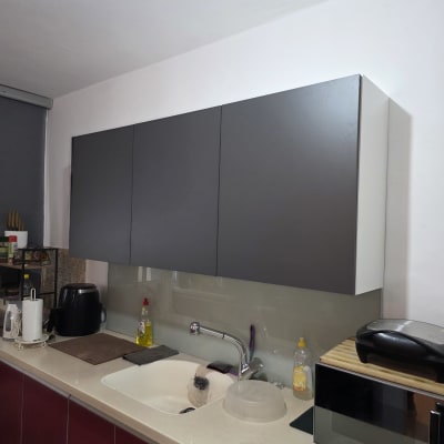 מטבח עם ארונות, כיור וברז, מכשירי חשמל וכלים.