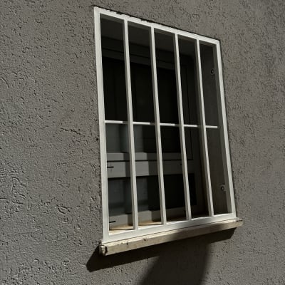 סורגי מתכת על חלון קיר בטון אפור