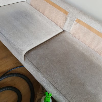 ספה עם כתמים, צינור שואב ובקבוק ניקוי ירוק