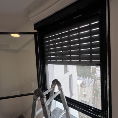 תריסים שחורים פתוחים חלקית עם סולם מתחת לחלון