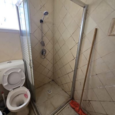 מקלחת ושירותים עם רצפה מלוכלכת ומגב