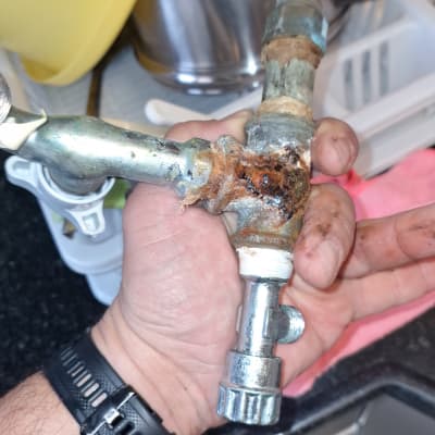 יד מחזיקה צינור מתכת חלוד עם ברז קטן
