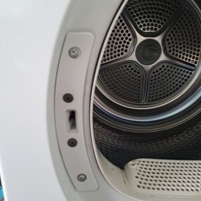 תוף מכונת כביסה עם דלת פתוחה וברגים