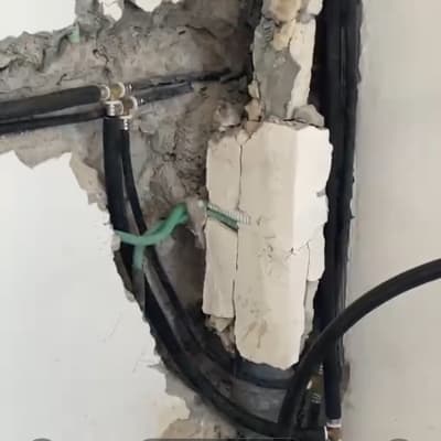 חשיפת צנרת מים בתוך קיר מבוקע במהלך עבודת תיקון אינסטלציה
