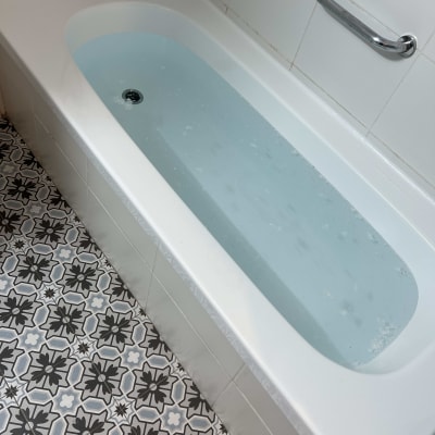 אמבטיה מלאה במים עם ידית אחיזה על הקיר