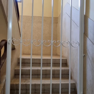 שער מתכת לבן עם עיטורים על גרם מדרגות