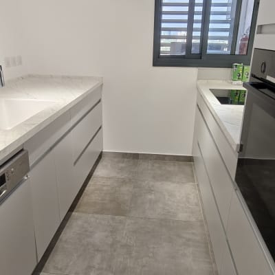 קירות מטבח מודרני צבועים בלבן נקי לצד משטחי שיש וארונות