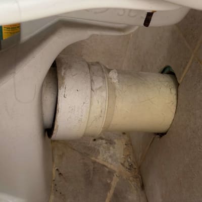 חיבור צינור ניקוז מפלסטיק מאחורי אסלה עומדת אל הקיר