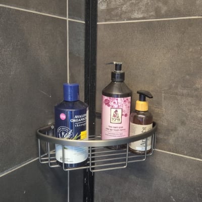 מדף מתכת בפינת מקלחת עם בקבוקי סבון