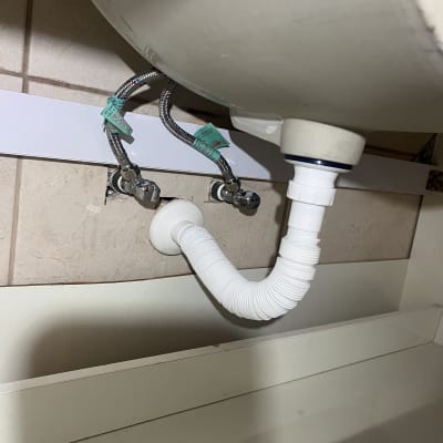 צינור ניקוז לבן מתחת לכיור עם חיבורים