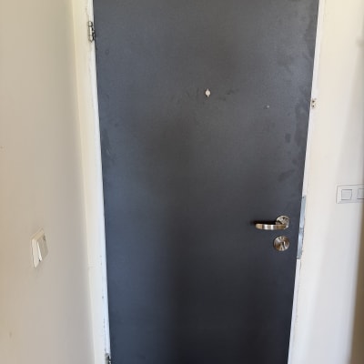 דלת מתכת עם ידית כסופה וקיר לבן