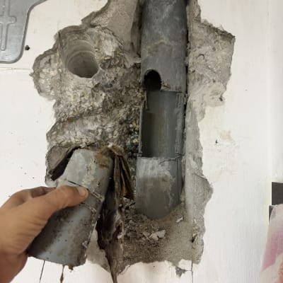 תמונה של צינור שבור בקיר עם יד אוחזת בו