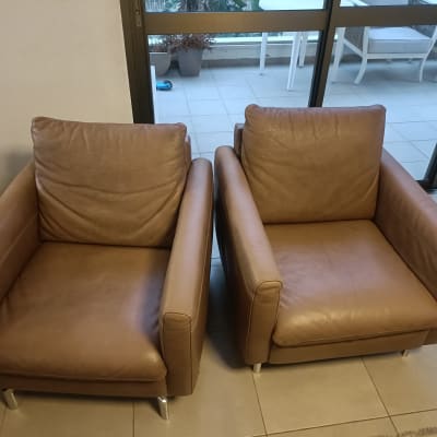 שתי כורסאות עור חומות נקיות לאחר ניקוי ספות עור בסלון