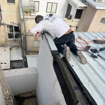 אדם מבצע איטום על גג עם יריעות ביטומניות