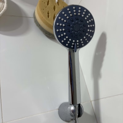 ראש מקלחת וספוג במקלחת על קיר אריחים לבן