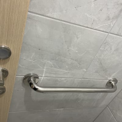 ידית אחיזה מתכתית על קיר אריחים בחדר אמבטיה