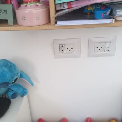 שקעי חשמל על קיר ליד מדף עם חפצים שונים