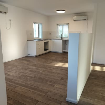 מטבח ריק עם רצפת עץ נקייה וקירות לבנים