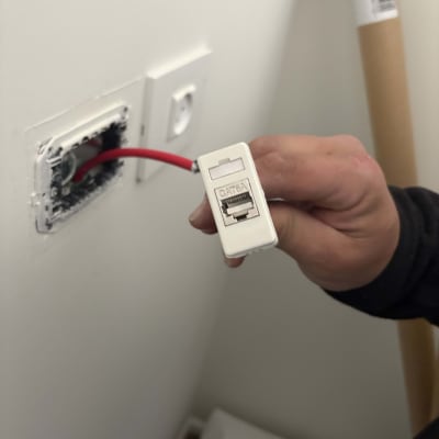 טכנאי מחזיק כבל רשת אדום עם מחבר CAT6A