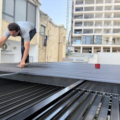 אדם עובד על פרגולה מאלומיניום עם מקדחה