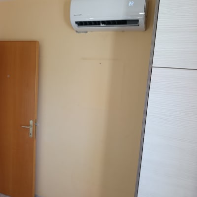 מזגן עילי אינוורטר מותקן על קיר בחדר ומציג טמפרטורה