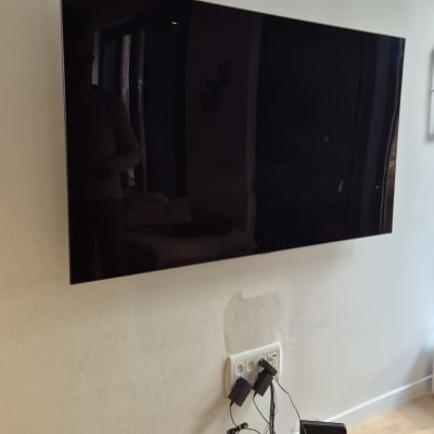 טלוויזיה תלויה על הקיר עם חוטים ושקעים חשמליים