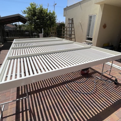 סוכך מתכת לבן על רגליים בחצר מרוצפת