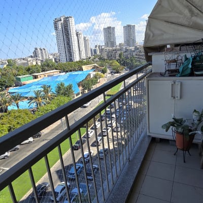 מרפסת עם רשת נגד יונים ונוף עירוני