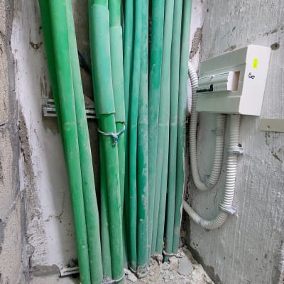 צינורות ירוקים ולוח חשמל בקיר בטון