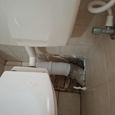 תמונה של שירותים עם צינור ותיקון קיר