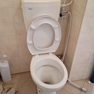 אסלה עם מכסה פתוח וצינור מים מחובר