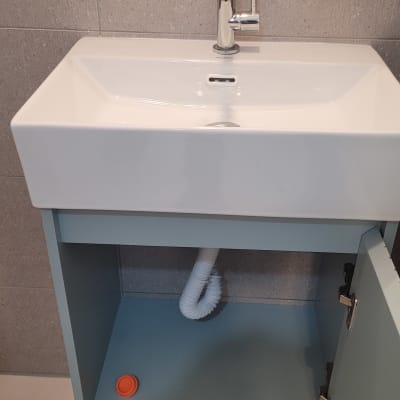 ארון אמבטיה מותקן עם כיור לבן, ברז וצינור ניקוז