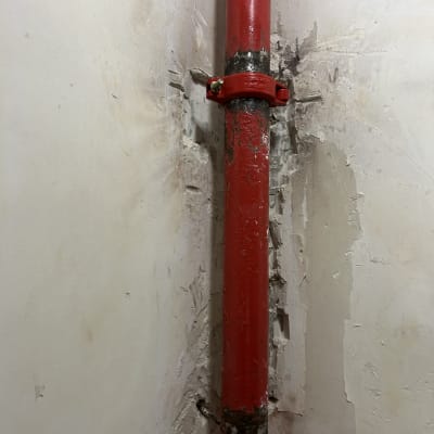 צינור כיבוי אש אדום עם תפסן על קיר