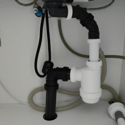 צנרת מתחת לכיור עם מחברים וצינורות פלסטיק
