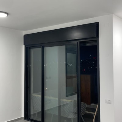 דלת זכוכית עם מסגרת שחורה ומטאטא בפינה