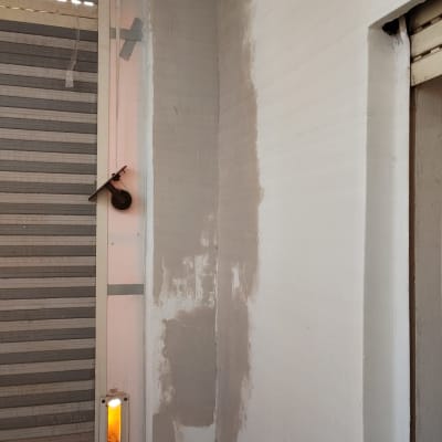 קיר צבוע חלקית ליד חלון עם תריסים