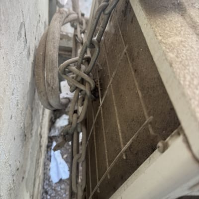 יחידת מזגן חיצונית עם שרשרת על קיר ישן