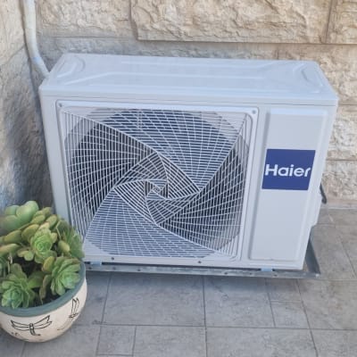 יחידת מזגן חיצונית של Haier ליד קיר אבן