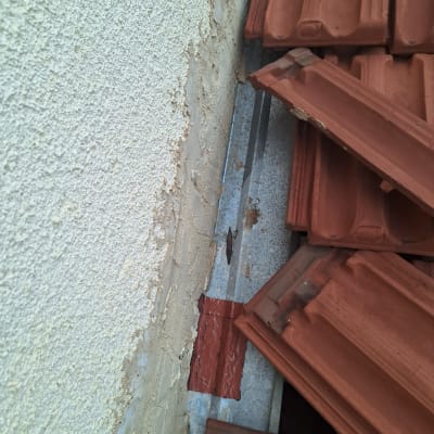 רעפים חומים מונחים על גג ליד קיר טיח